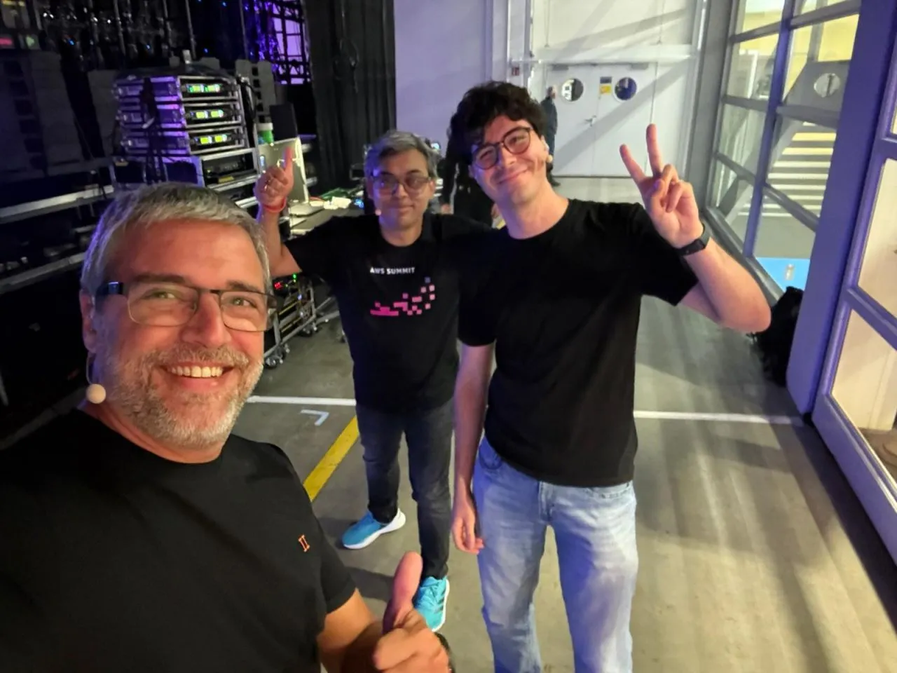 Alejandro Morcillo, Alberto Antoñanzas and Pinaki Banerjee backstage at AWS Summit Zurich 2026 with microphones on, grinning and throwing peace signs before presenting session AIM302